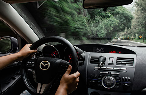 A woman sitting in a car with a steering wheel