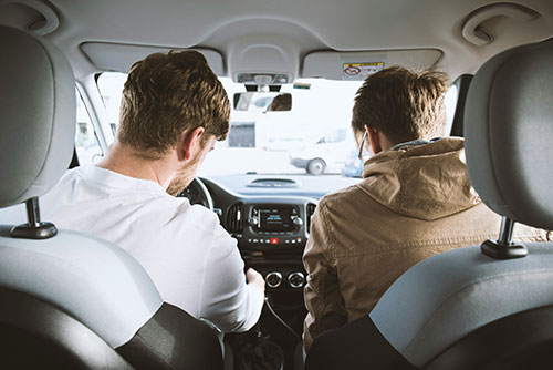 Two young men, one showing the other how to drive