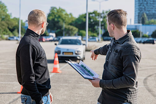 Driving instructor witha clipboard showing a man what to do
