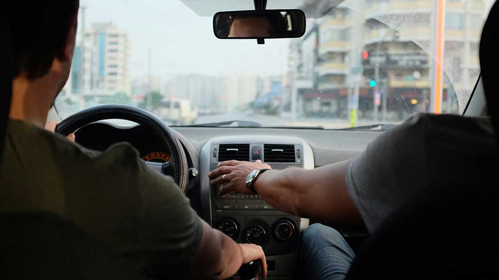 Driving Instructor pointing to his car
