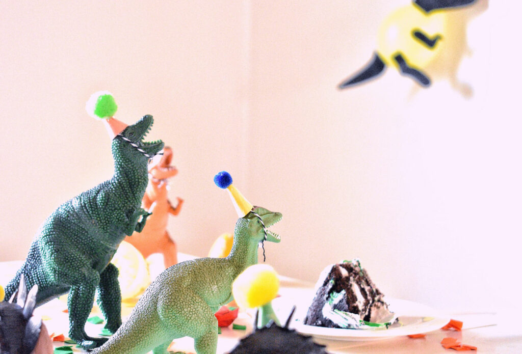 Shows a group of toy dinosaurs with party hats