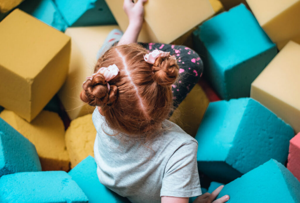 shows a girl sitting in a play area - how to set up childrens soft play