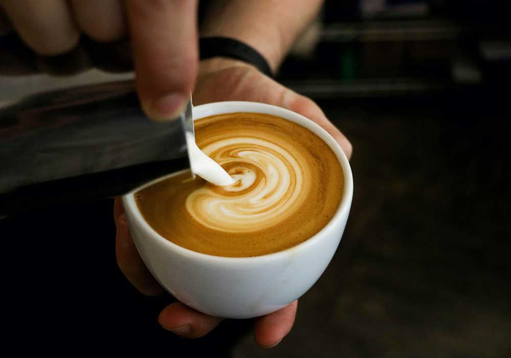 Cafe insurance - Shows a barista pouring milk into coffee