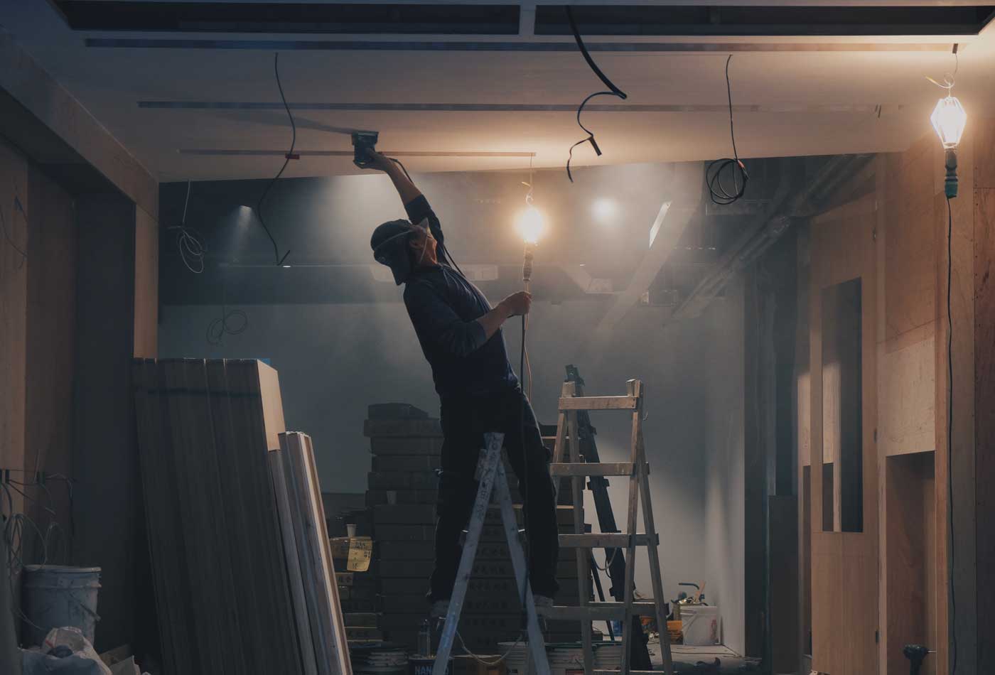 Shows a construction worker marking a ceiling