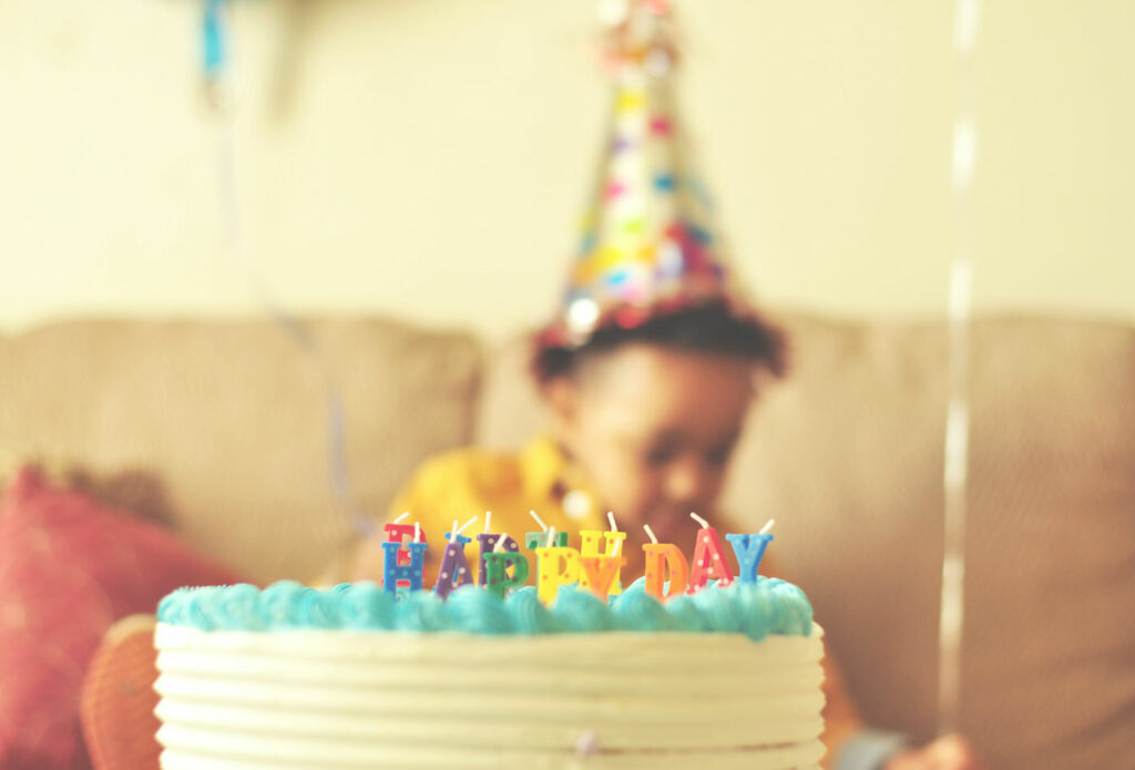 shows a close up image of a child behind a cake - Planning a children's party
