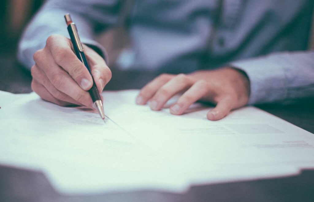 shows an image of someone writing on a notepad - Professional Medical Malpractice Insurance