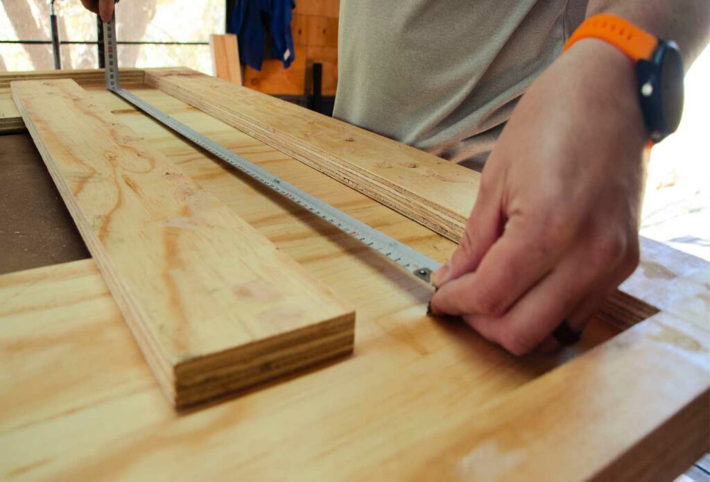 shows a carpenter measuring out a piece of wood