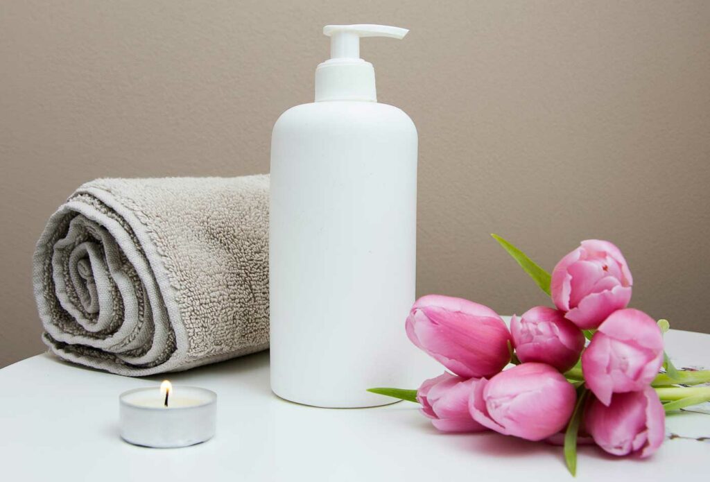 shows hand lotion and a towel next to pink flowers - hair & beauty salon insurance