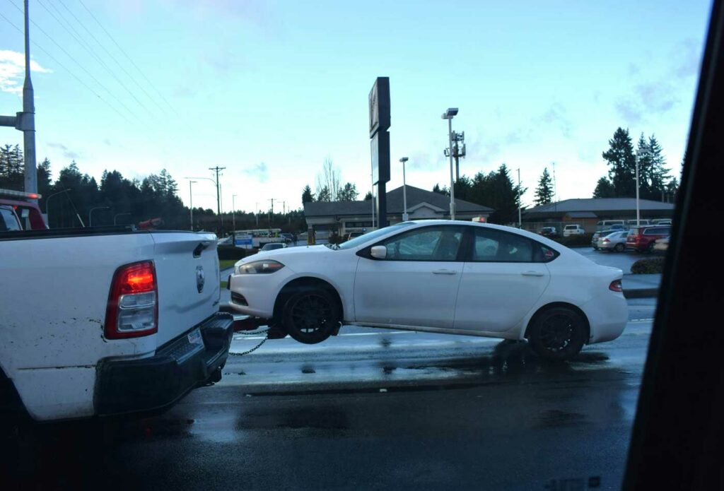 shows a white car being towed to a van