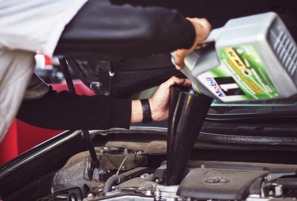 shows a mechanic adding oil to a car - starting a successful automotive business