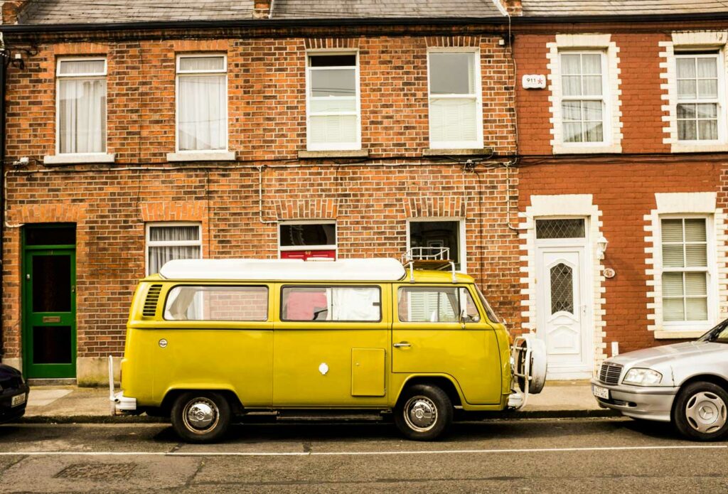 shows a yellow campervan outside a house 