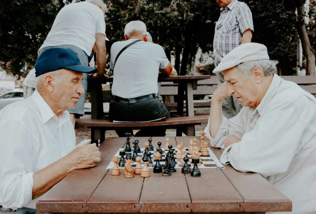 shows two old people playing a game of chess