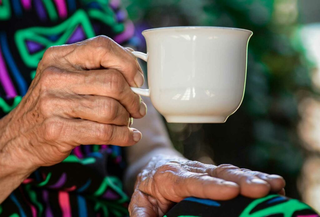 shows an old lady holding a cup of tea - care and nursing home insurance