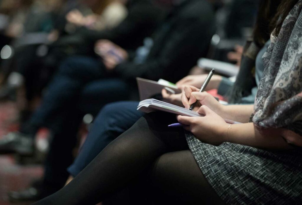 shows people writing on their notebooks - conference event insurance